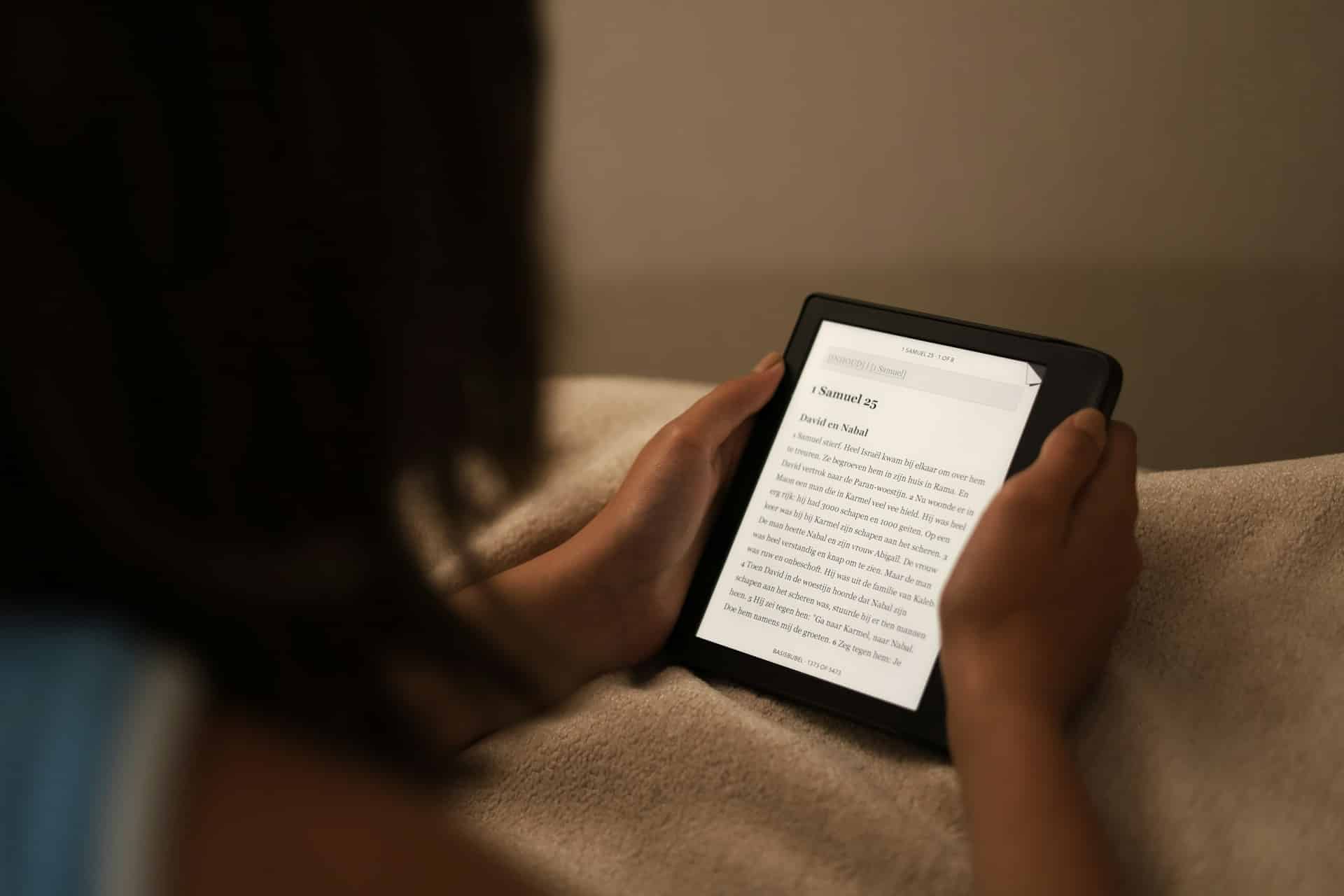 Une femme lit la Bible sur une tablette dans son lit - Photo de Worshae sur https://unsplash.com/fr/photos/une-personne-tenant-une-tablette-GlUibDBVkvI