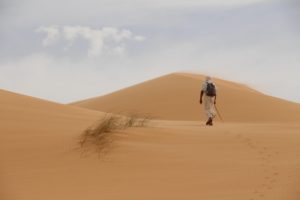 Un homme s'avance en montant, seul, dans des dunes de sable - Image par franck JUILLARD de https://pixabay.com/fr/photos/d%C3%A9sert-sable-voyageur-dunes-nature-7162926/