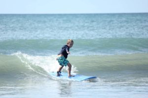 Un jeune garçon commençant à surfer sur une petite vague - Image par jcsaenz de https://pixabay.com/fr/photos/le-surf-plage-l%C3%A9t%C3%A9-sport-vacances-1411688/