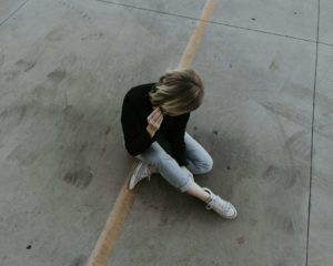 Une femme seule, assise par terre sur une ligne jaune, met ses écouteurs pour ne rien entendre - Photo de Austin Kehmeier sur https://unsplash.com/fr/photos/femme-assise-sur-le-trottoir-reZXCdgXVeA