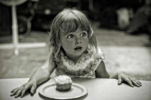 Photo en noir et blanc d'une fillette devant un petit gâteau et ouvrant de grands yeux comme devant une formidable surprise - Photo de Nathan Bingle sur https://unsplash.com/fr/photos/fille-devant-le-gateau-K9MaGDSbOTg