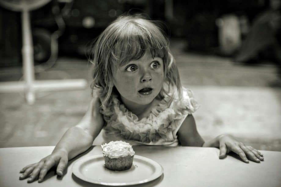 Photo en noir et blanc d'une fillette devant un petit gâteau et ouvrant de grands yeux comme devant une formidable surprise - Photo de Nathan Bingle sur https://unsplash.com/fr/photos/fille-devant-le-gateau-K9MaGDSbOTg