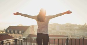 Une femme en prière de louange sur son balcon au dessus de la ville - Image par Pexels de https://pixabay.com/fr/photos/balcon-femme-debout-ensoleillement-1834990/