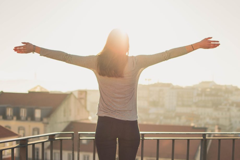Une femme en prière de louange sur son balcon au dessus de la ville - Image par Pexels de https://pixabay.com/fr/photos/balcon-femme-debout-ensoleillement-1834990/