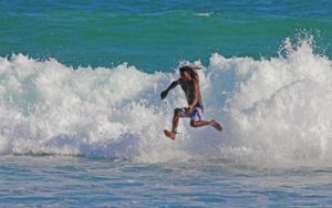 Un jeune surfeur aux cheveux longs semble marcher sur l'eau - Image par David de https://pixabay.com/fr/photos/surf-cours-sport-adr%C3%A9naline-3223752/