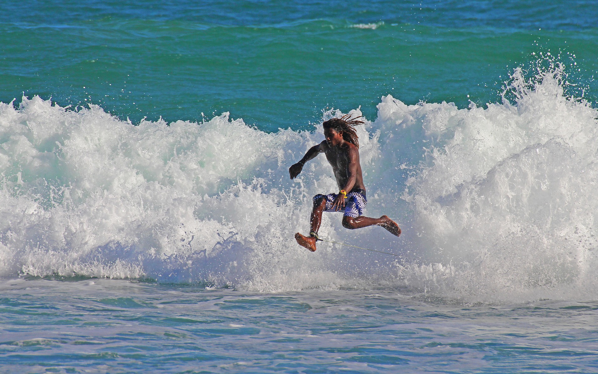 Un jeune surfeur aux cheveux longs semble marcher sur l'eau - Image par David de https://pixabay.com/fr/photos/surf-cours-sport-adr%C3%A9naline-3223752/