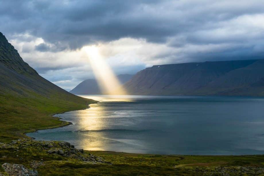 Un rayon de soleil passe à travers des nuages et éclairent un bras de mer - Photo de Davide Cantelli sur https://unsplash.com/fr/photos/reflet-du-soleil-sur-leau-calme-pres-des-montagnes-vertes-H3giJcTw__w
