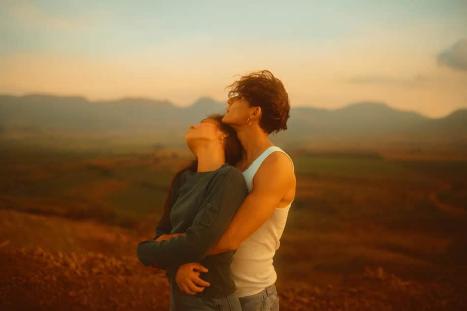 photo colorisée d'un couple avec un homme portant des boucles d'oreilles enlaçant une femme heureuse - Photo de Mariela Ferbo sur https://unsplash.com/fr/photos/un-homme-et-une-femme-debout-dans-un-champ-jOSY3kGfdFg