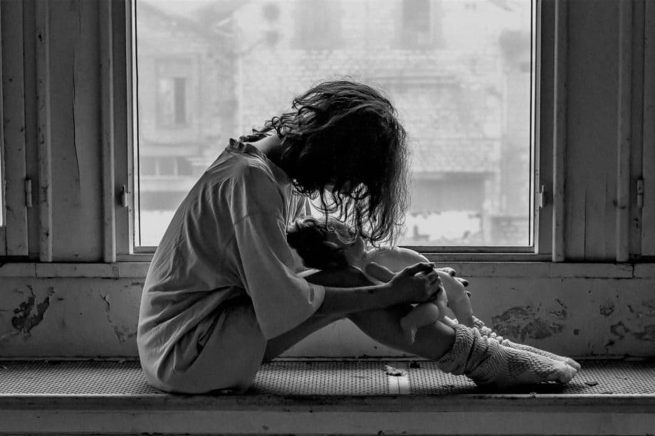 Photo en noir et blanc d'une femme, assise devant une fenêtre, désespérée, prostrée, échevelée - Photo https://pixabay.com/fr/photos/femme-solitude-tristesse-%C3%A9motions-1958723/