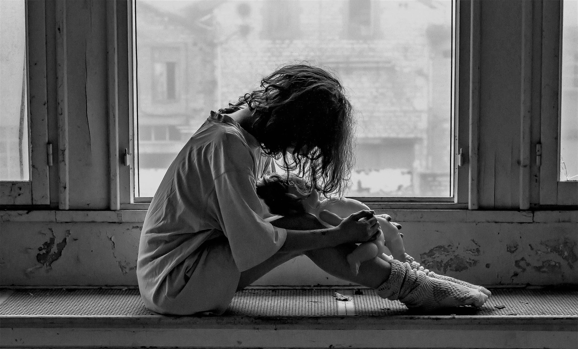Photo en noir et blanc d'une femme, assise devant une fenêtre, désespérée, prostrée, échevelée - Photo https://pixabay.com/fr/photos/femme-solitude-tristesse-%C3%A9motions-1958723/