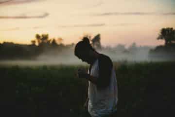 Un jeune homme dans la nature, au coucher du soleil, en pleine réflexion ou prière - Photo de Jake Young sur https://unsplash.com/fr/photos/homme-portant-un-haut-raglan-noir-et-blanc-sur-un-champ-dherbe-verte-IsCT80pMA8k