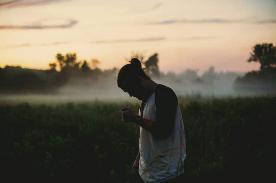 Un jeune homme dans la nature, au coucher du soleil, en pleine réflexion ou prière - Photo de Jake Young sur https://unsplash.com/fr/photos/homme-portant-un-haut-raglan-noir-et-blanc-sur-un-champ-dherbe-verte-IsCT80pMA8k