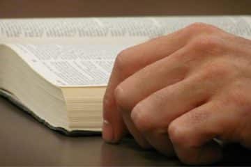 Une bible ouverte et la main de la personne qui est en train de la lire - Image par Deborah Hudson de https://pixabay.com/fr/photos/livre-ouvert-bible-ouverte-bible-2809972/