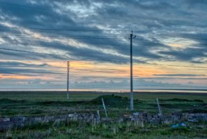 Aube dans la campagne, avec des lignes électriques en premier plan, et quelques nuages - Photo de Ridger sur https://unsplash.com/fr/photos/un-champ-avec-un-poteau-et-un-poteau-dedans-9yTKi9H050Q