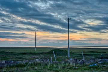 Aube dans la campagne, avec des lignes électriques en premier plan, et quelques nuages - Photo de Ridger sur https://unsplash.com/fr/photos/un-champ-avec-un-poteau-et-un-poteau-dedans-9yTKi9H050Q