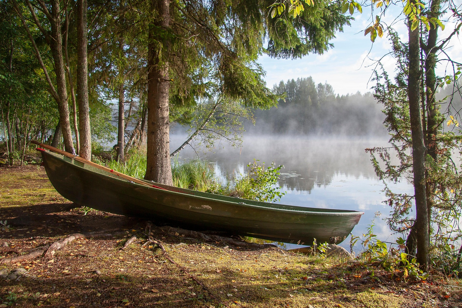 Un bateau prêt à être emprunté pour naviguer sur un lac calme, avec du soleil et une légère brume, et de beaux arbres - Image par Tapani Hellman de https://jecherchedieu.ch/wp-content/uploads/2025/09/boat-6579441_1920.jpg