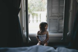 Une fillette souriante et maquillée en chat est assise devant une fenêtre à moitié ouverte sur le jour qui se lève - Photo de Caroline Hernandez sur https://unsplash.com/fr/photos/fille-assise-pres-de-la-fenetre-pendant-la-journee-r1xJuG7rD60