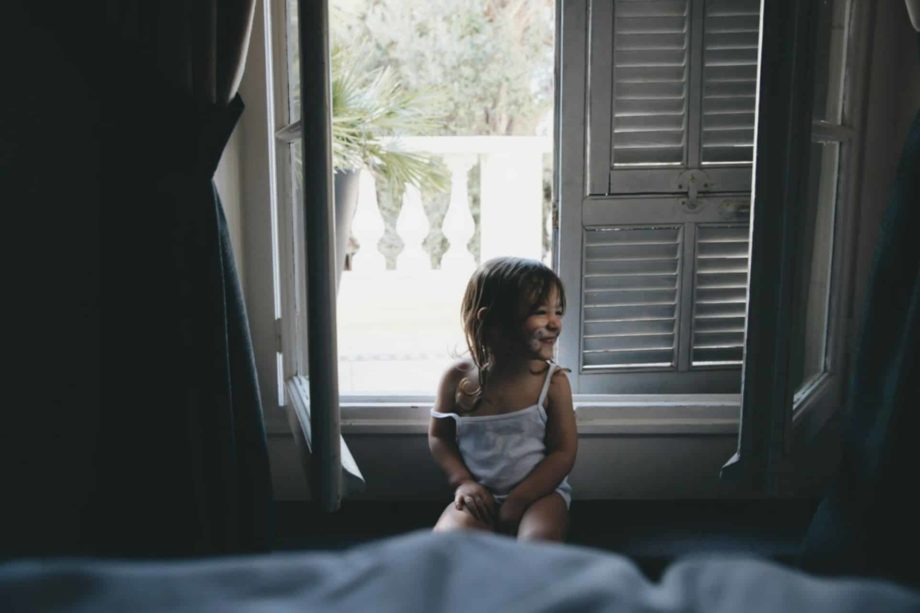 Une fillette souriante et maquillée en chat est assise devant une fenêtre à moitié ouverte sur le jour qui se lève - Photo de Caroline Hernandez sur https://unsplash.com/fr/photos/fille-assise-pres-de-la-fenetre-pendant-la-journee-r1xJuG7rD60