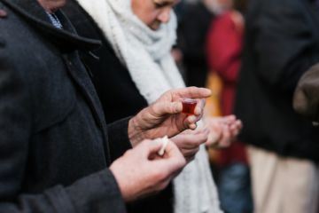 Des personnes en train de communion avec un bout de pain et une petite coupe de vin - Photo de Nico Smit sur https://unsplash.com/fr/photos/femme-en-hijab-blanc-tenant-la-main-des-personnes-9UW_8aVN8mA