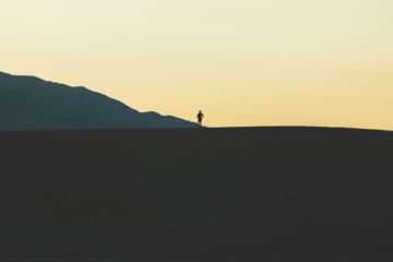 une personne vue de loin en marche sur la crête d