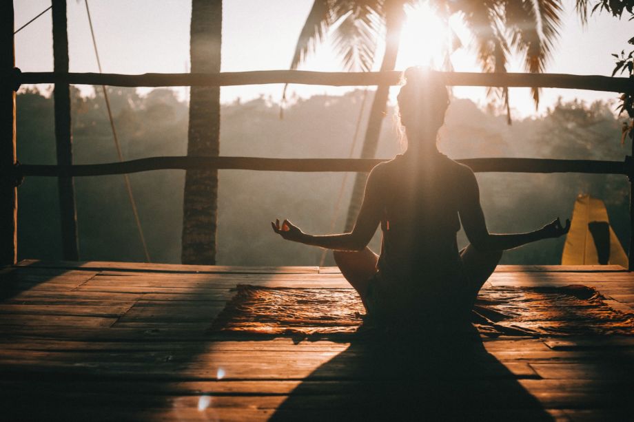 Une femme en pleine méditation sur une terrasse en bois au lever du soleil en Indonésie - Photo de Jared Rice sur https://unsplash.com/fr/photos/femme-en-debardeur-noir-assise-sur-un-quai-en-bois-brun-pendant-la-journee-xce530fBHrk