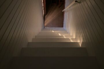 Un rayon de lumière perce sur un escalier descendant entre des murs modernes - Photo de Justus Hinz sur https://unsplash.com/fr/photos/un-escalier-menant-a-un-couloir-UZXtxxDwp4I