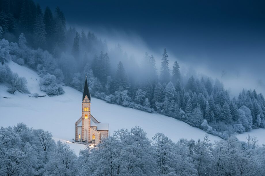 Une église illuminée dans un paysage enneigé au milieu des arbres - Photo de Pascal Debrunner sur https://unsplash.com/fr/photos/une-eglise-nichee-dans-un-paysage-montagneux-enneige--4iFZizAAZ8
