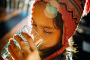 Une petite fille nomade dans le désert boit un grand verre d'eau - Photo de Johnny McClung sur https://unsplash.com/fr/photos/photographie-selective-de-leau-potable-dune-fille-uDM99xirqI4