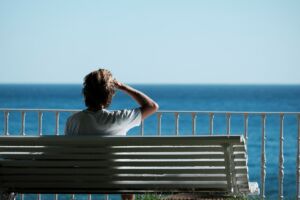 Un homme assis sur un bac face à la mer regarde l'horizon - Photo de Miguel A Amutio sur https://unsplash.com/fr/photos/homme-assis-sur-un-banc-pres-dun-plan-deau-pendant-la-journee-8EB0jEOP_4c
