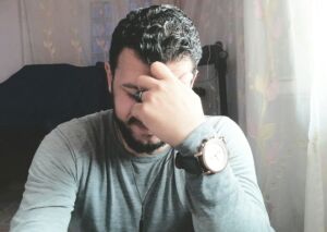 Un homme assis à son bureau, concentré sur ses pensées, et souriant - Photo de Muhmed Alaa El-Bank sur https://unsplash.com/fr/photos/une-personne-avec-la-main-sur-le-visage-tm3MZSG1gEg