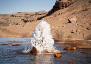 Une photo du Crystal Geyser, Utah, USA - Photo de Alex Moliskisur https://unsplash.com/fr/photos/un-gros-rocher-sortant-dun-plan-deau-4Z_sILTknDU