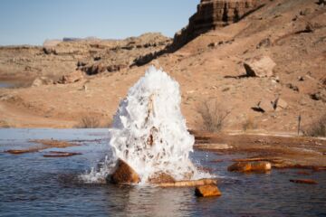 Une photo du Crystal Geyser, Utah, USA - Photo de Alex Moliskisur https://unsplash.com/fr/photos/un-gros-rocher-sortant-dun-plan-deau-4Z_sILTknDU