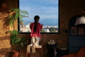 Une fillette montée sur une chaise pour mieux contempler par la fenêtre - Photo de hoylee songsur https://unsplash.com/fr/photos/femme-regardant-par-la-fenetre-les-montagnes-et-le-ciel-4SI4nHako5Q