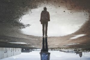 Une personne debout dans un terrain industriel se reflète dans une flaque d'eau - Photo de Randy Jacobsur https://unsplash.com/fr/photos/reflexion-de-lhomme-sur-la-photographie-de-plan-deau-A1HC8M5DCQc