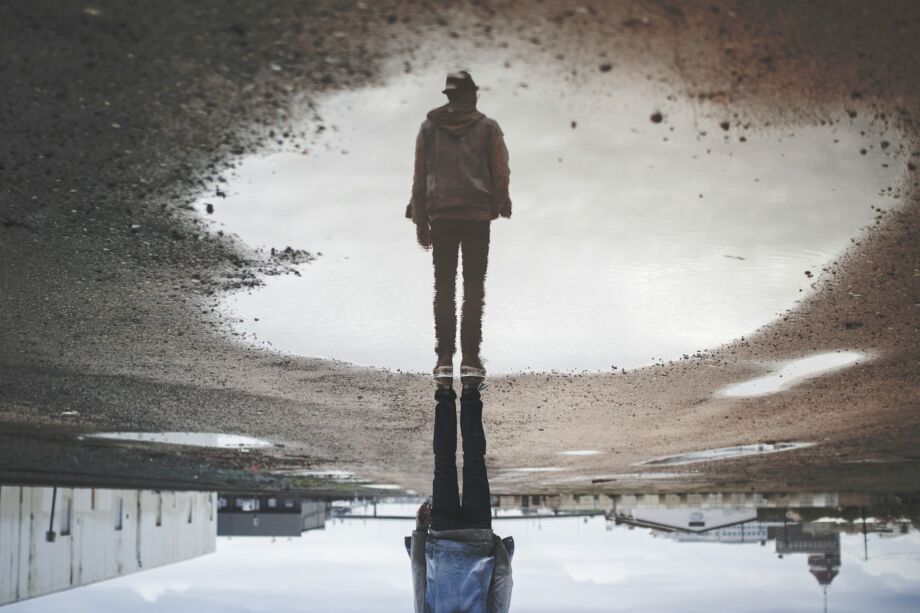 Une personne debout dans un terrain industriel se reflète dans une flaque d'eau - Photo de Randy Jacobsur https://unsplash.com/fr/photos/reflexion-de-lhomme-sur-la-photographie-de-plan-deau-A1HC8M5DCQc