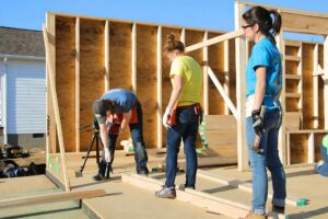 Des jeunes homme et femmes construisent une maison - Photo de Brad Weaver sur https://unsplash.com/fr/photos/un-couple-de-femmes-debout-sur-un-plancher-en-bois-MrZWtlKDKRw