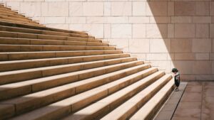 un tout petit enfant regarde avec attention la première marche d'un grand escalier en pierre - Photo de Jukan Tateisi sur https://unsplash.com/fr/photos/enfant-en-bas-age-debout-devant-lescalier-en-beton-beige-bJhT_8nbUA0