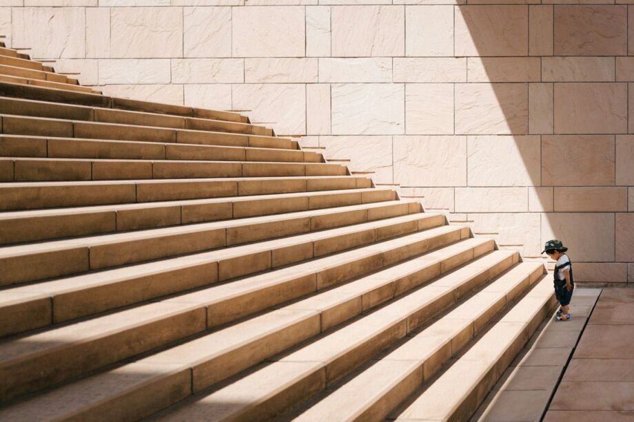 un tout petit enfant regarde avec attention la première marche d'un grand escalier en pierre - Photo de Jukan Tateisi sur https://unsplash.com/fr/photos/enfant-en-bas-age-debout-devant-lescalier-en-beton-beige-bJhT_8nbUA0