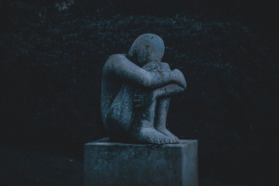 Une statue représentant un homme recroquevillé dans la pénombre d'un parc - Photo de K. Mitch Hodge sur https://unsplash.com/fr/photos/homme-etreignant-sa-statue-de-genou-IqSaG9zv2e0