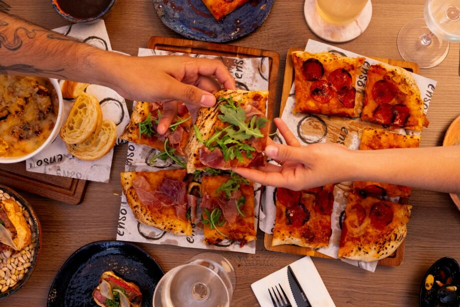 Une main tend une petite part de pizza à une personne qui la prend - Photo de Juan Pablo Lara sur https://unsplash.com/fr/photos/des-gens-partageant-diverses-pizzas-et-entrees-autour-dune-table-wVd7ZqPl5nk